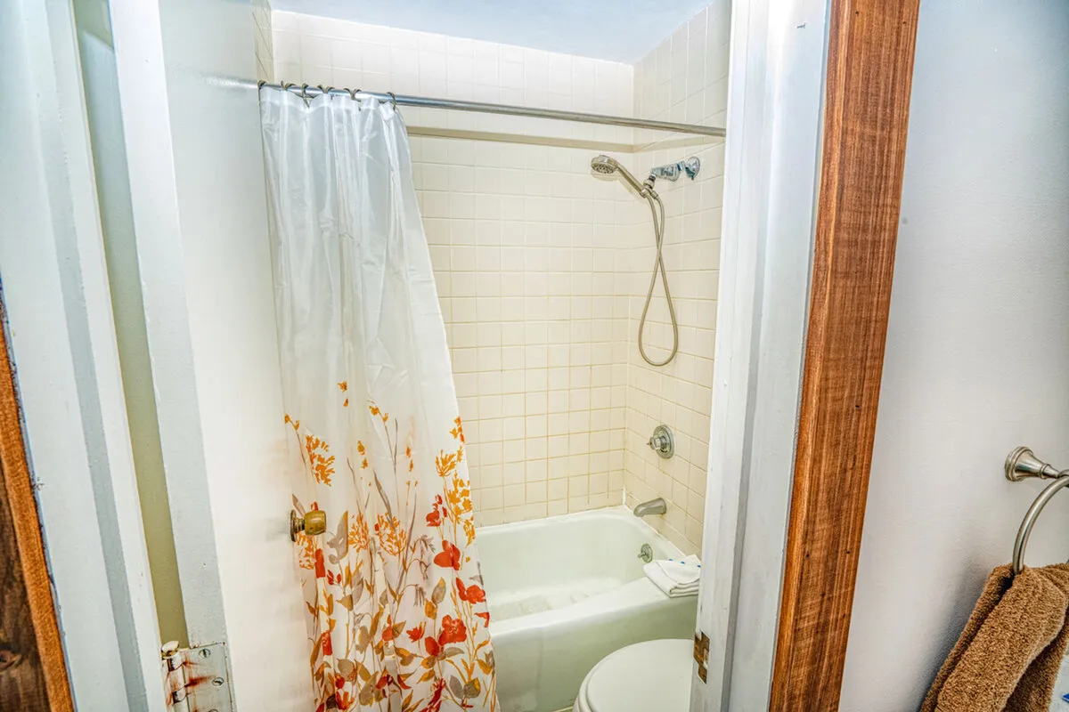 A well-appointed bathroom with a bathtub, shower curtain, and neatly arranged towels create a sense of comfort. The scene invites thoughts of refreshing showers or relaxing baths after a day of adventure.