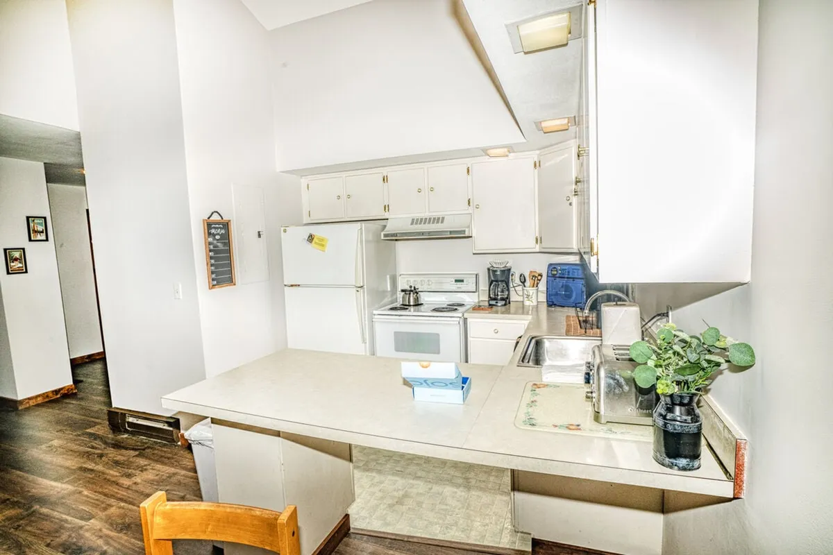 A bright kitchen with a central island, modern appliances, and a window letting in natural light. The layout invites both cooking and socializing, with clear sightlines to adjoining spaces.
