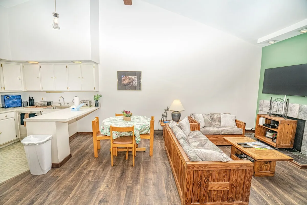 A welcoming open-concept space that combines a dining table, kitchen area, sofa, fireplace, and TV. The unified layout encourages socializing, dining, and relaxation in one harmonious setting.